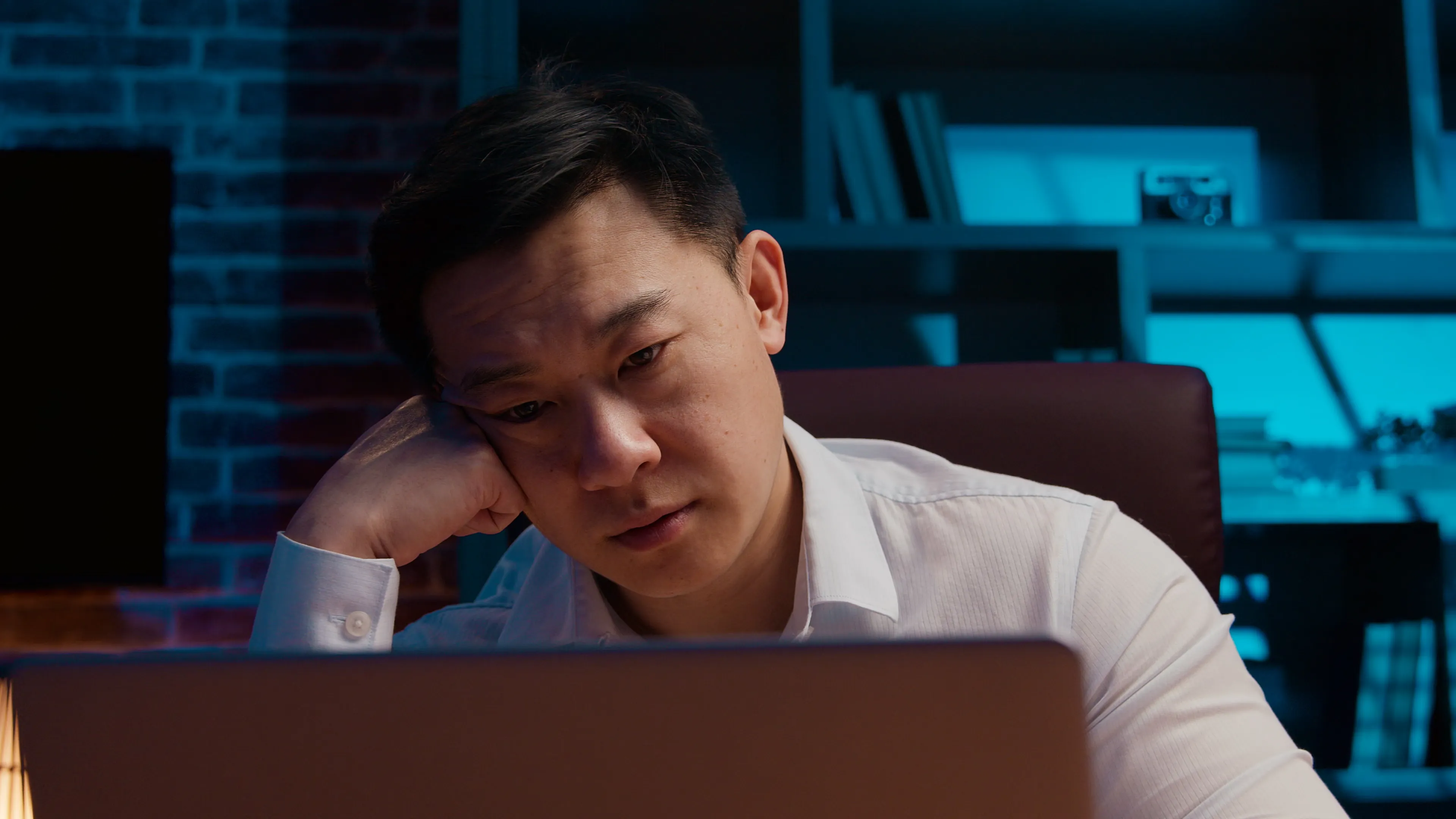 Person sitting back from a laptop in a darkened office